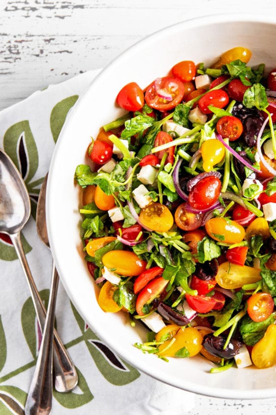 Large bowl of Tomato, Red Onion, Watercress, Feta and Olive Salad.