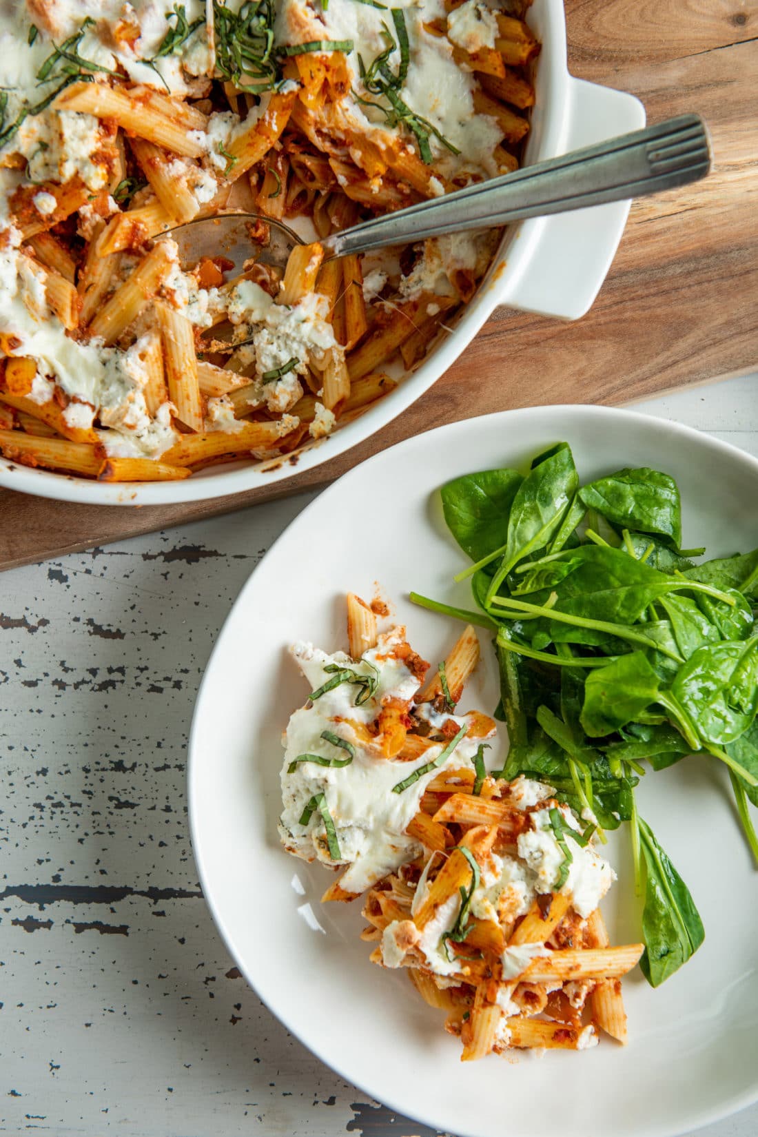 White plate of Baked Pasta with Bolognese Sauce and greens.