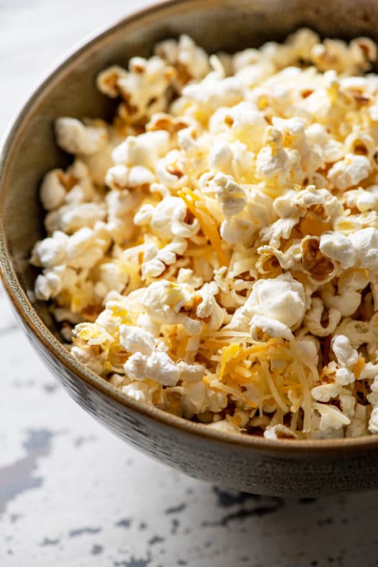 Popcorn in a bowl with shredded cheese.