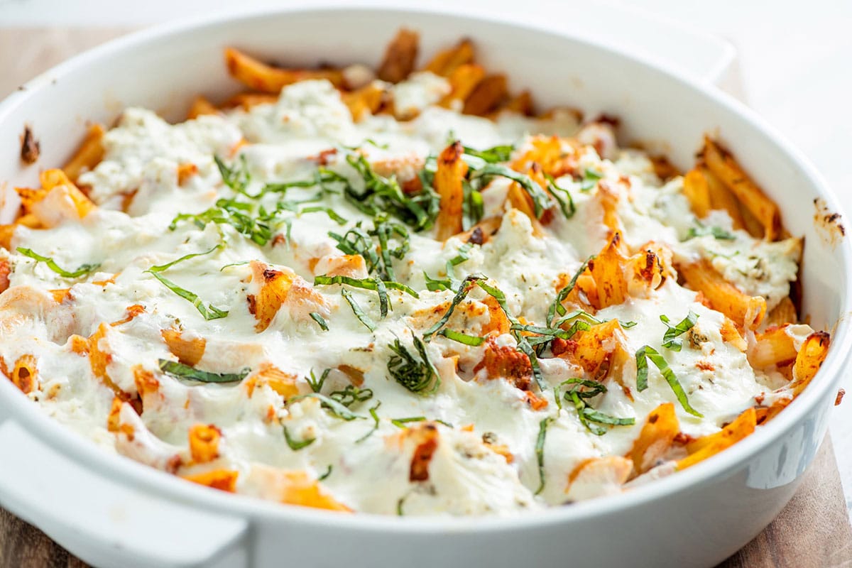 Pasta casserole in baking dish topped with fresh basil.