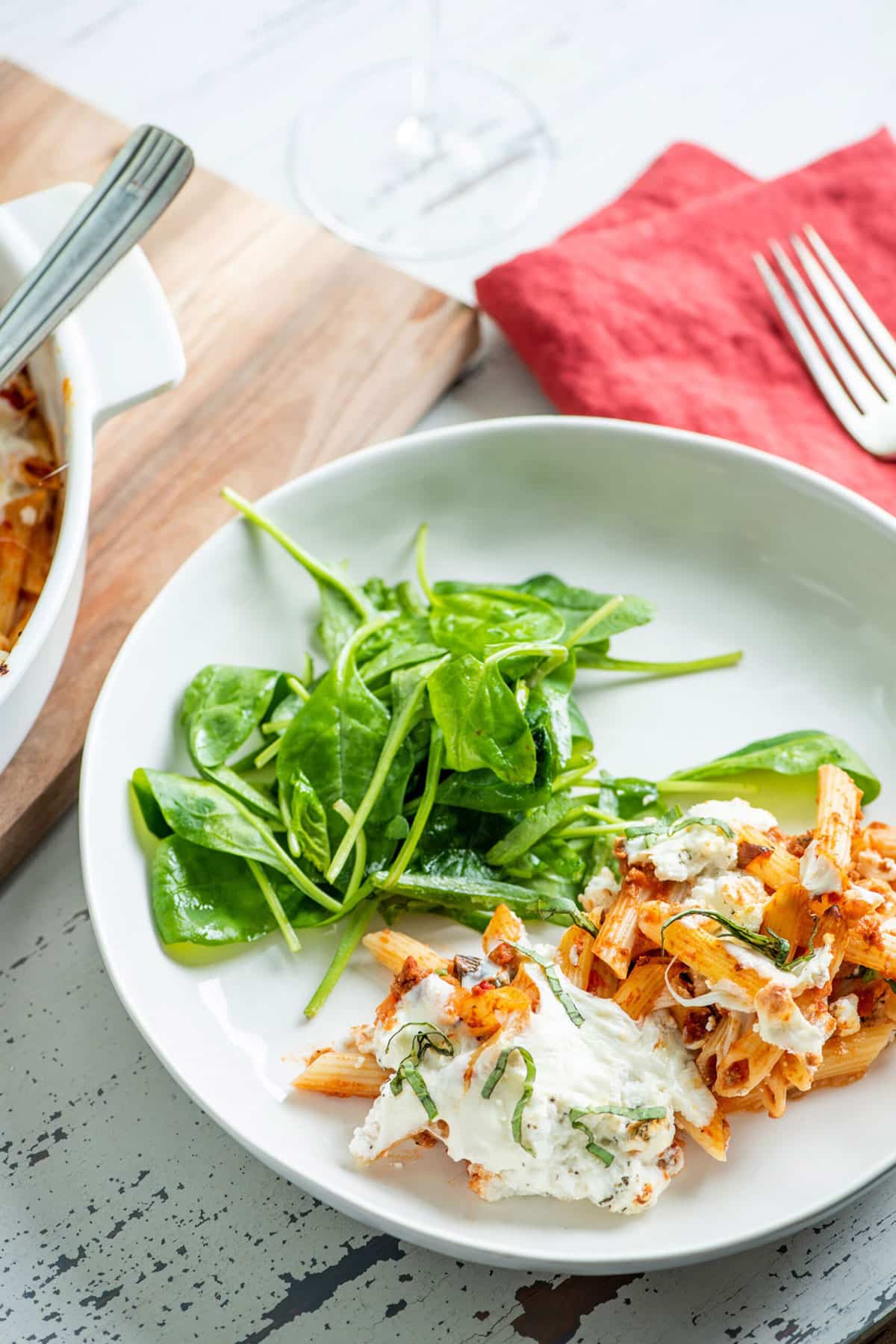 Baked Pasta with Bolognese Sauce on a plate with greens.