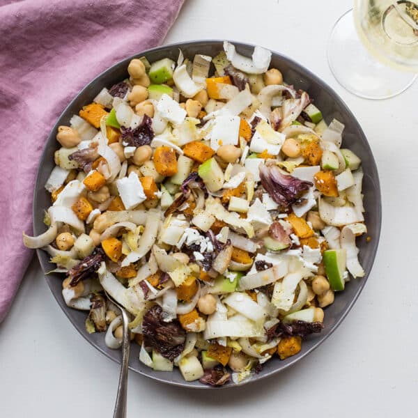 Serving dish of chopped winter salad on table with pink napkin.
