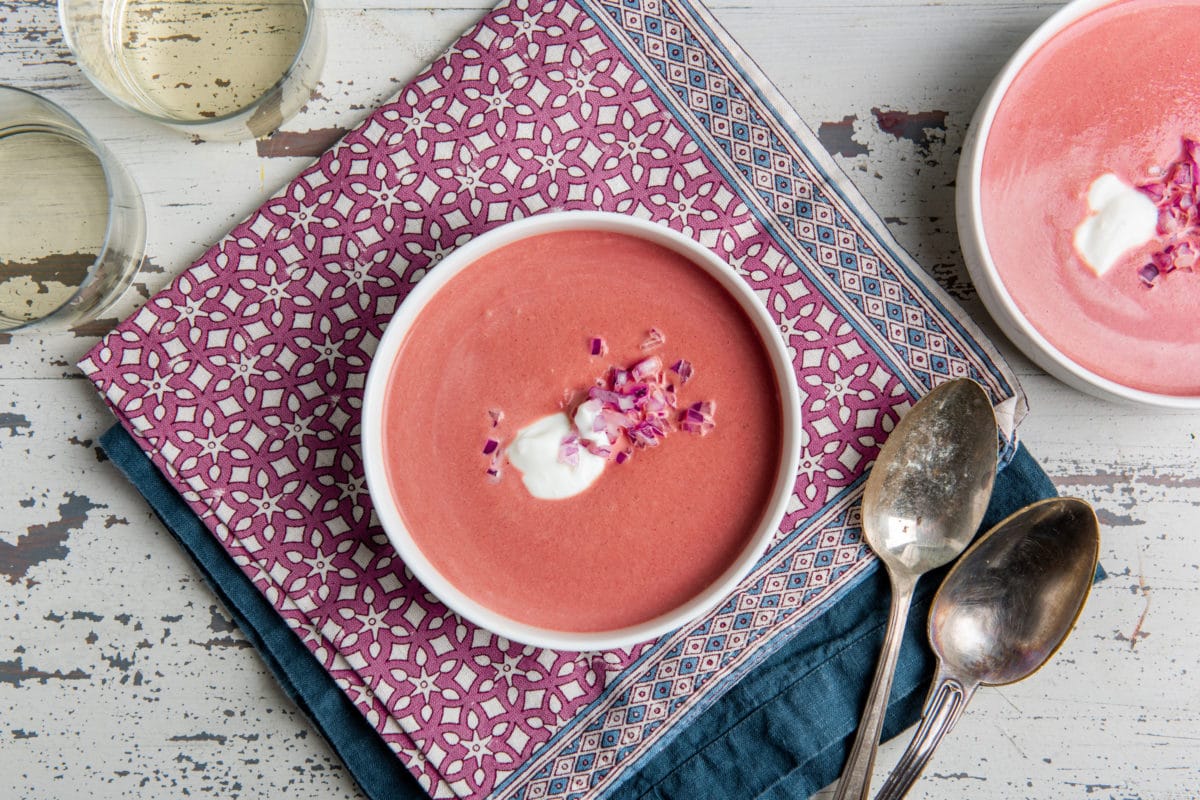 Bowl of Creamy Roasted Beet Soup topped with red onion and sour cream.