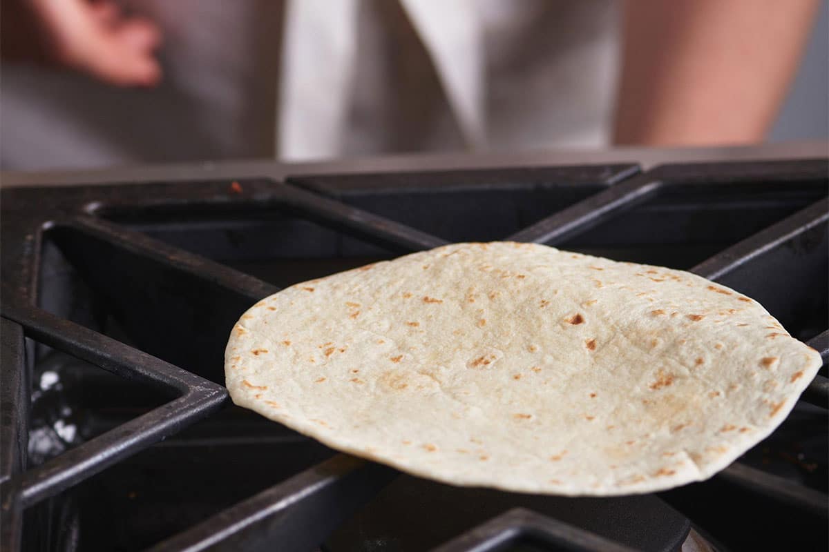 Tortilla warming directly on a gas stove.