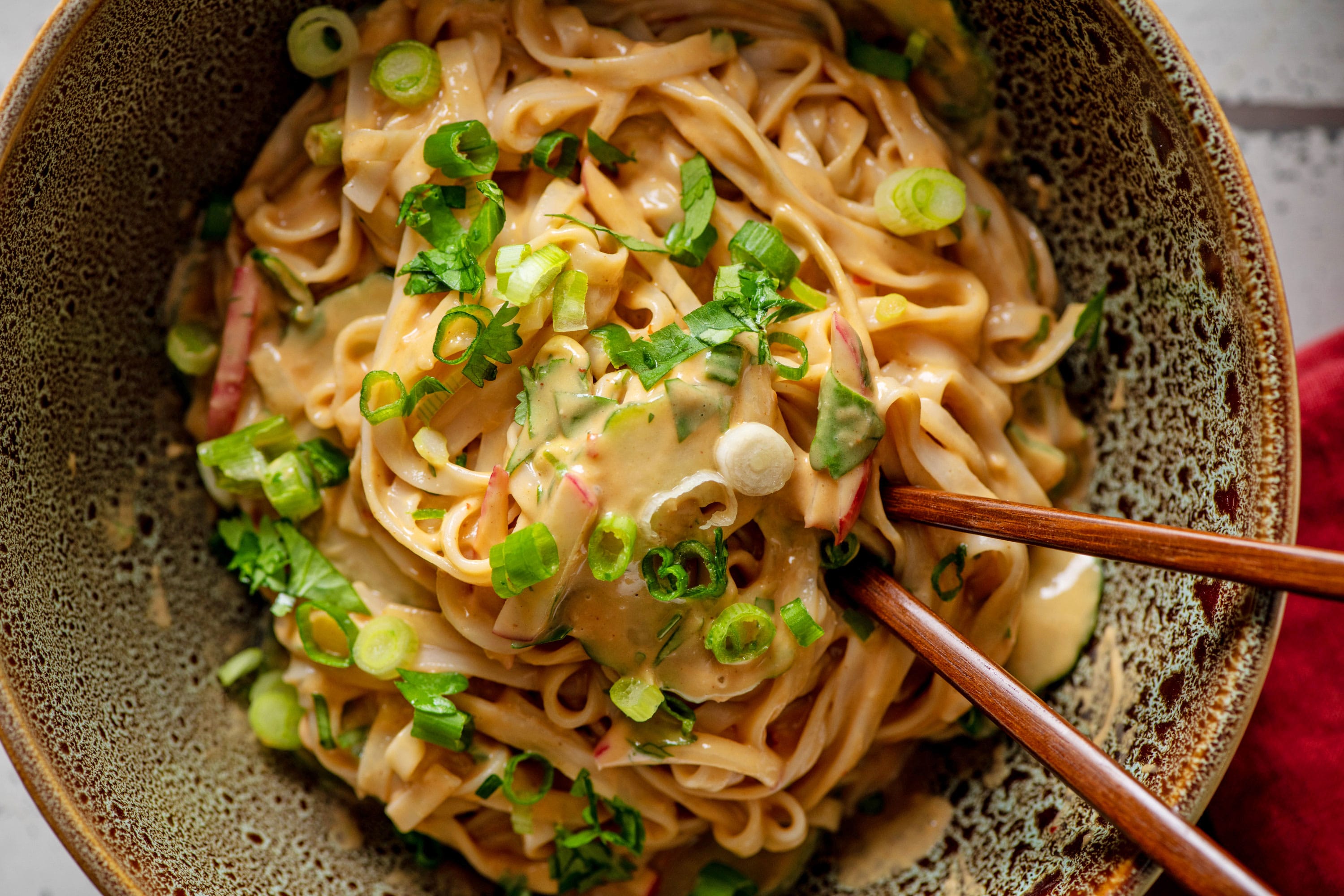 Noodles with Peanut Sauce in a bowl with chopsticks.