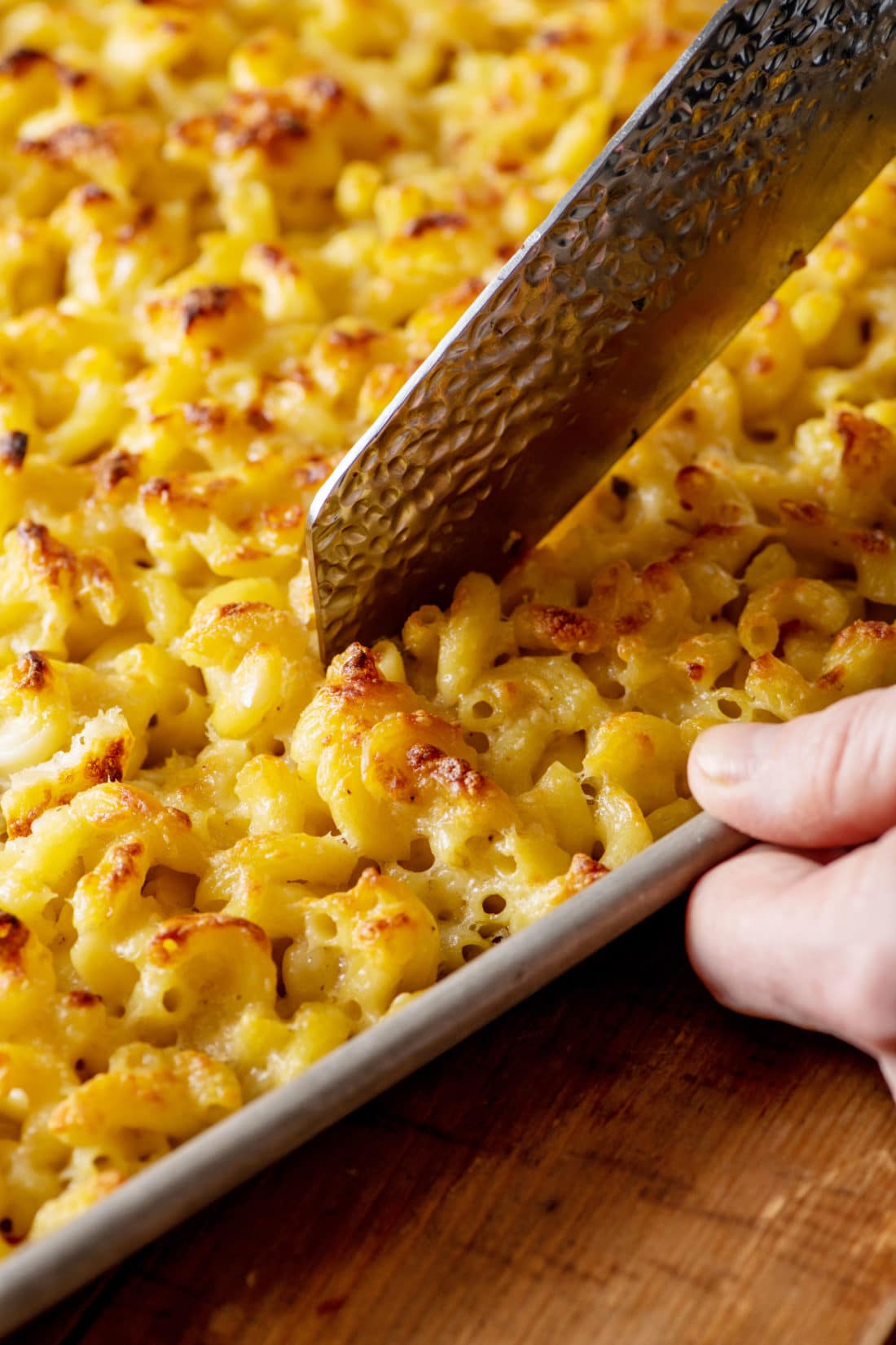 Knife cutting Sheetpan Macaroni and Cheese into Squares.