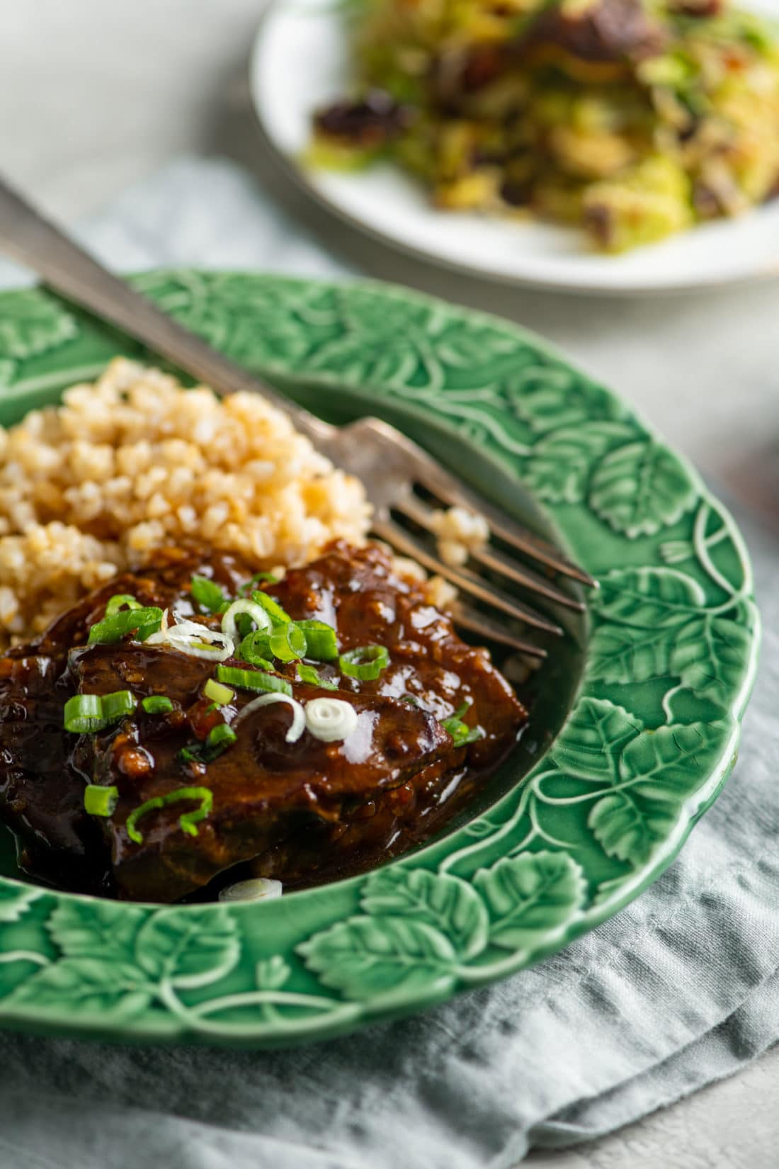 Green plate of Teriyaki Beef Tip Steaks and brown rice.