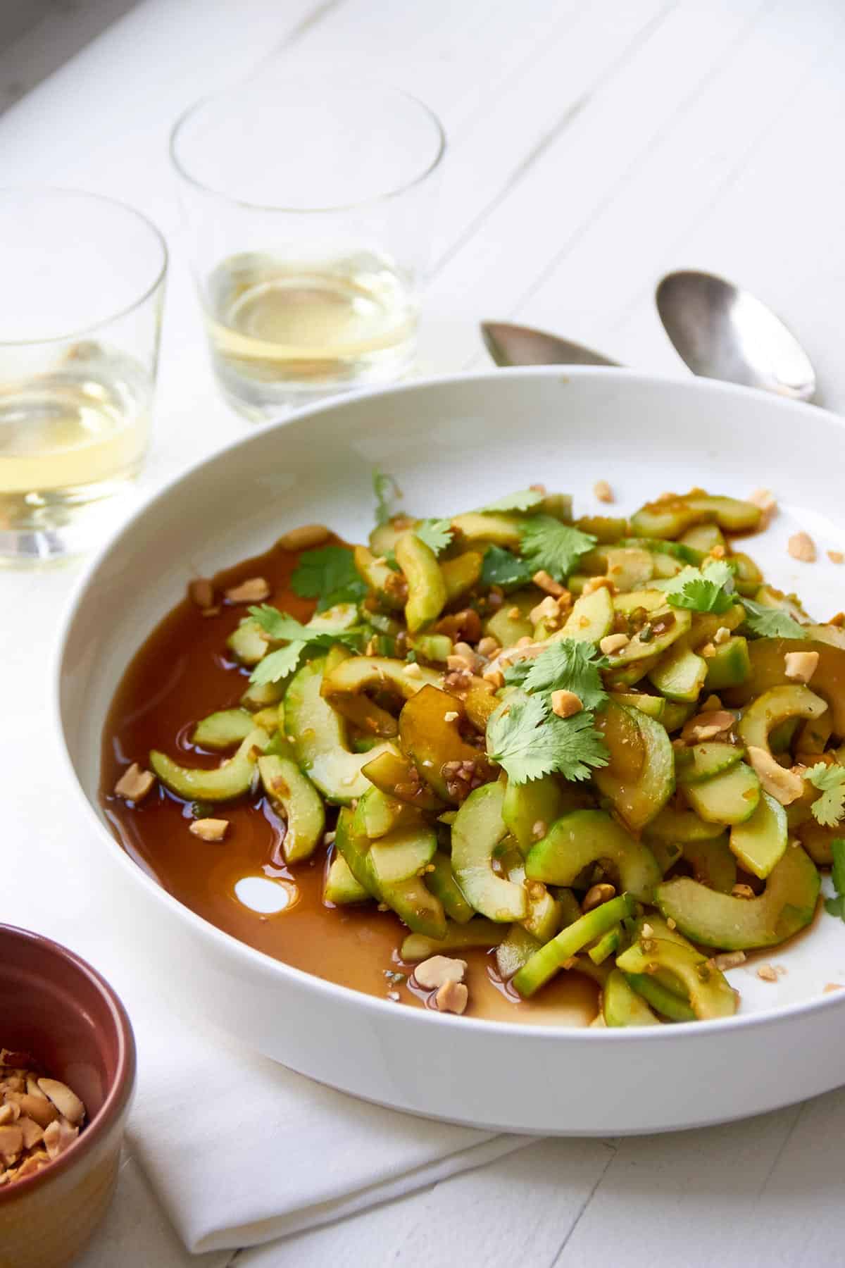 Cucumber salad with Thai sauce in white bowl on table.