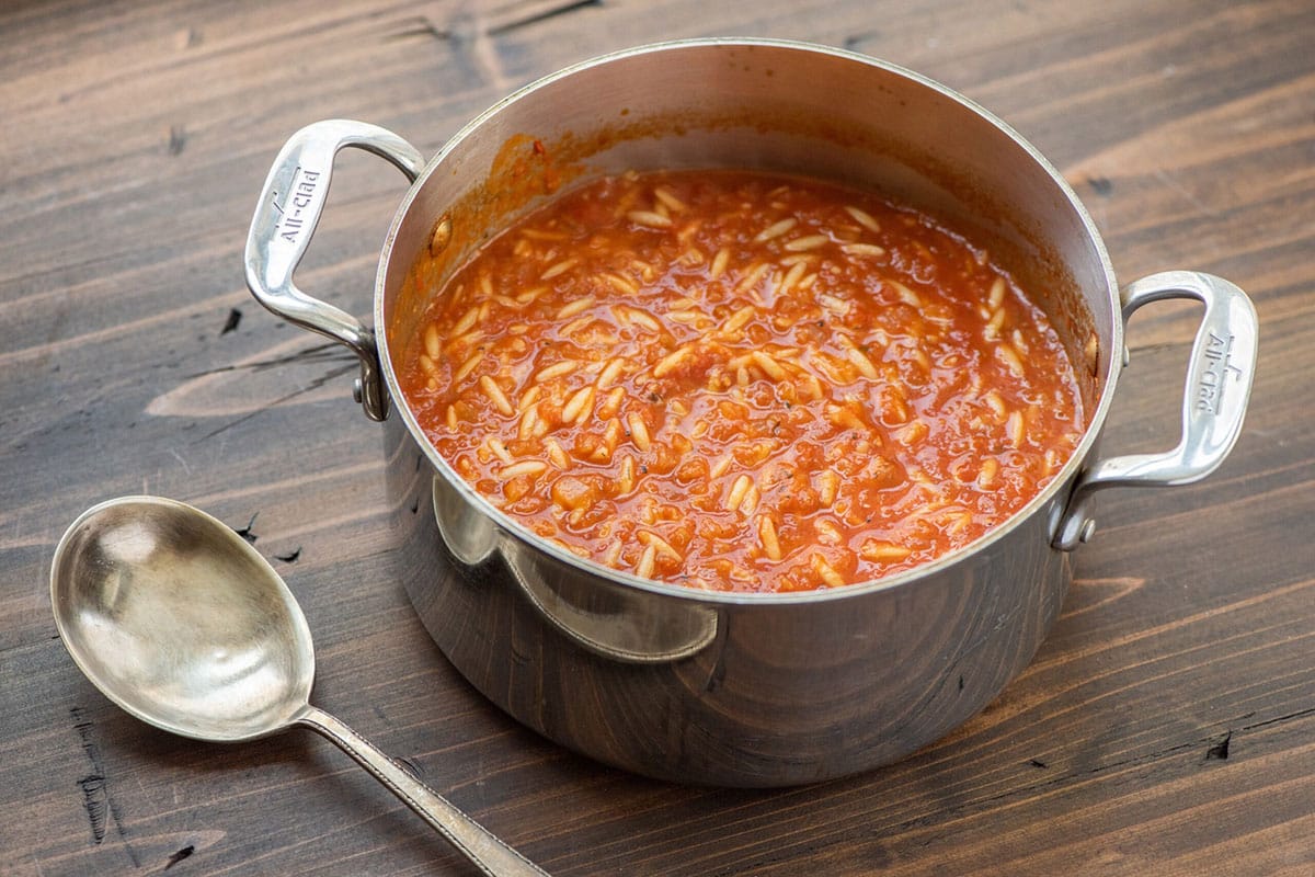 Tomato soup with orzo and dill in large pot on table.
