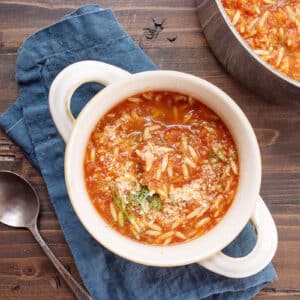 Bowl of Tomato, Orzo and Dill Soup on a blue cloth napkin.