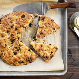 Golden brown dried cherry scone on parchment-lined pan with knives.