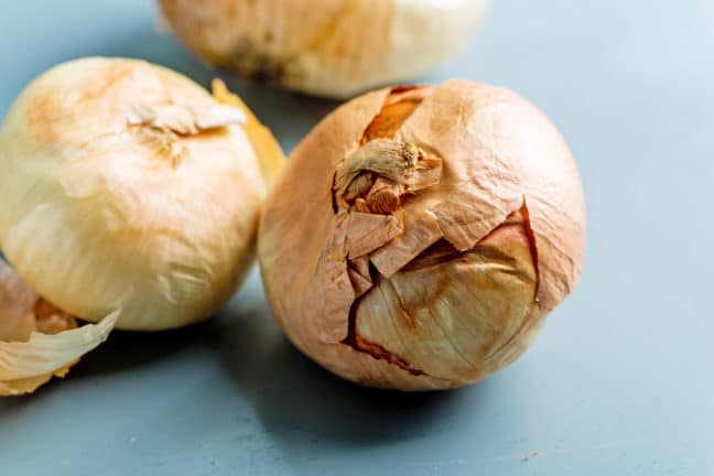 Golden Vidalia Onions sitting on a blue table.