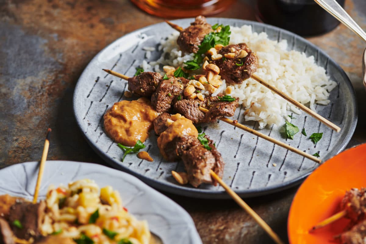 Lamb Satay, rice, and peanut sauce on a plate.