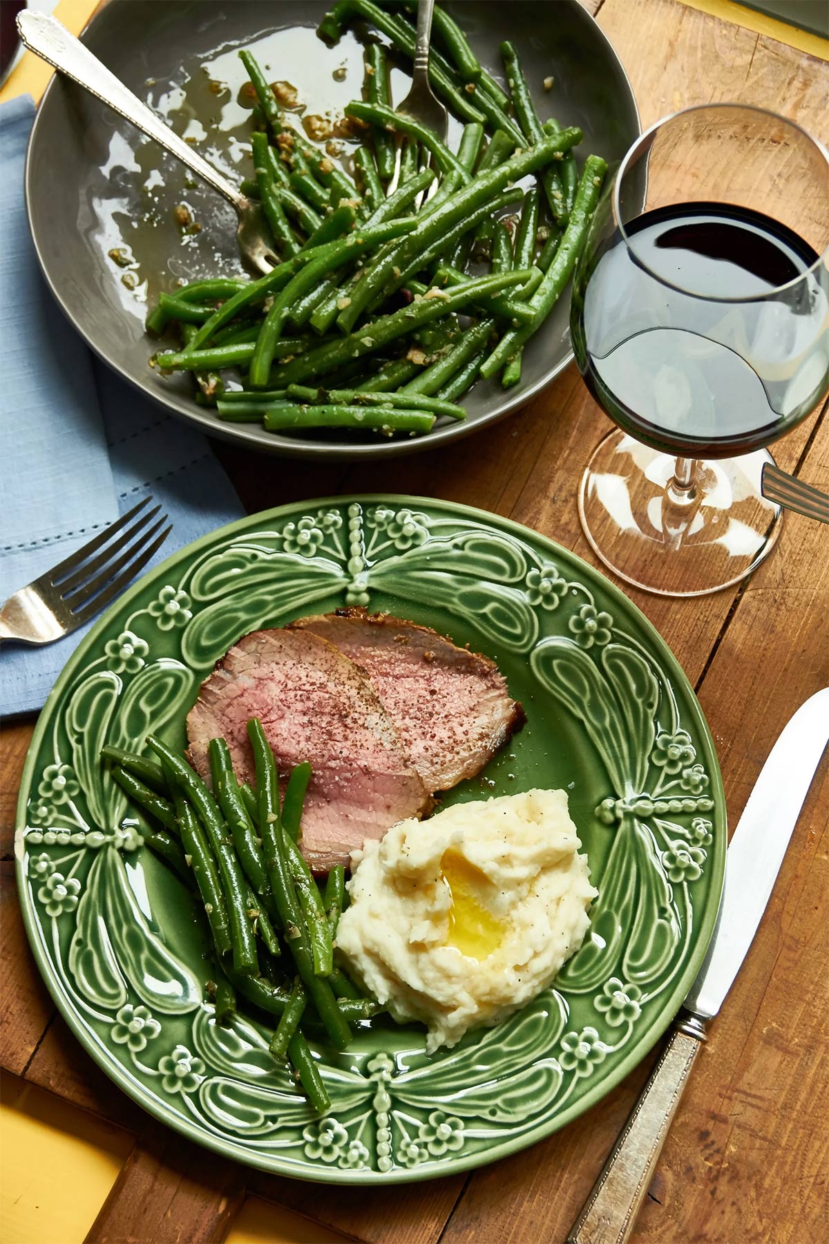 Roast Beef with Mustard Garlic Crust and Horseradish Sauce on a plate with beans and mashed potatoes.