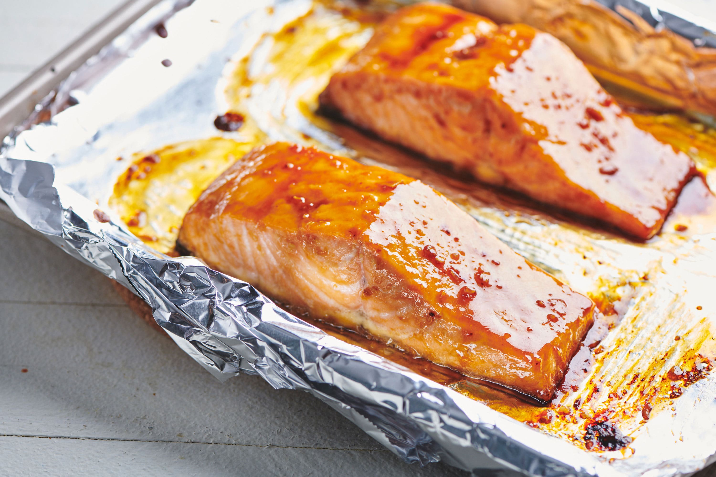 Baked honey-ginger glazed salmon on foil-lined baking sheet.