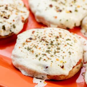 English Muffin Pizzas on an orange platter.