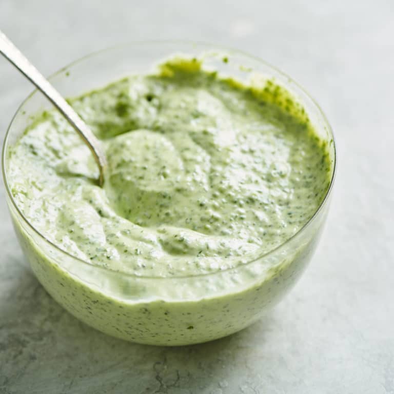 Green, Herbed Mayonnaise in a glass bowl with a spoon.