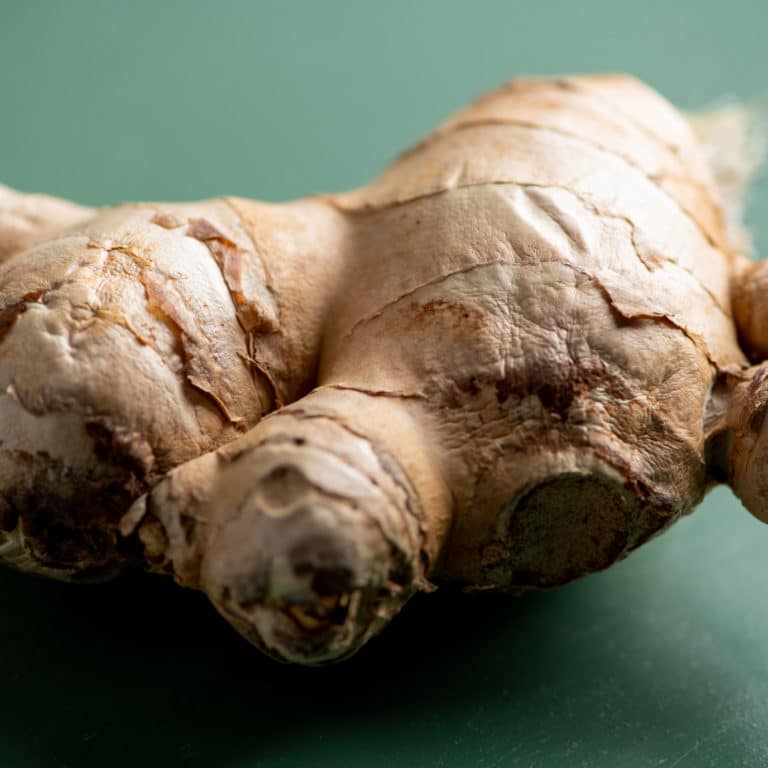Fresh ginger root on green table.
