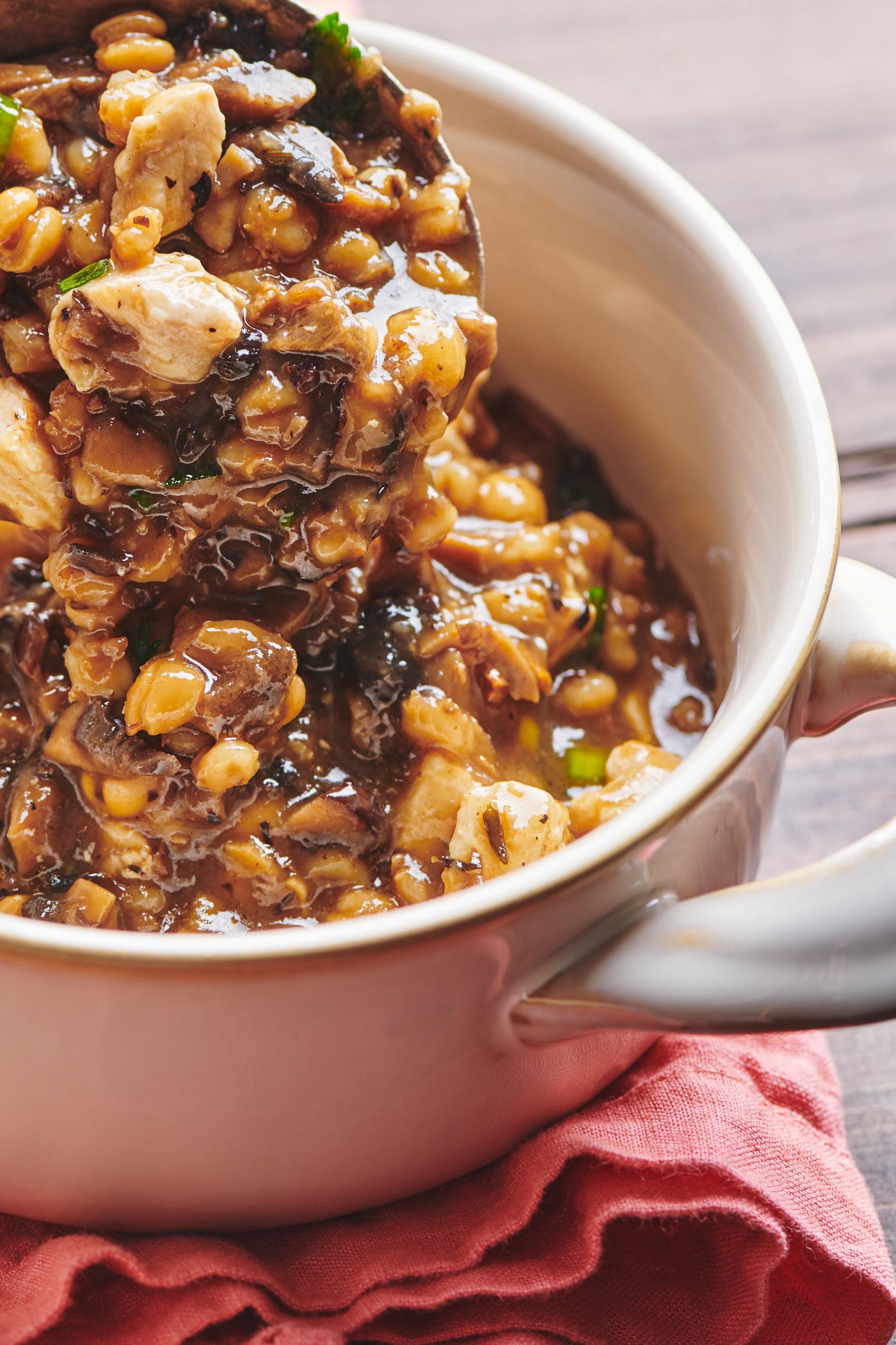 Scooping Chicken, Barley and Shiitake Mushroom Soup into white crock.