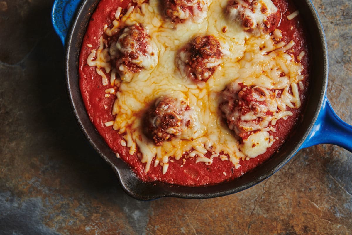 Meatball and melted cheese in a pan.