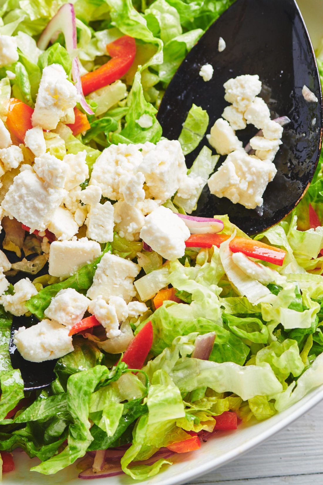 Spoon putting Queso Fresco on a Romaine Salad.