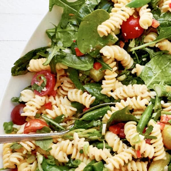 Simple Vegetarian Spring Pasta Salad in white serving platter with spoon.