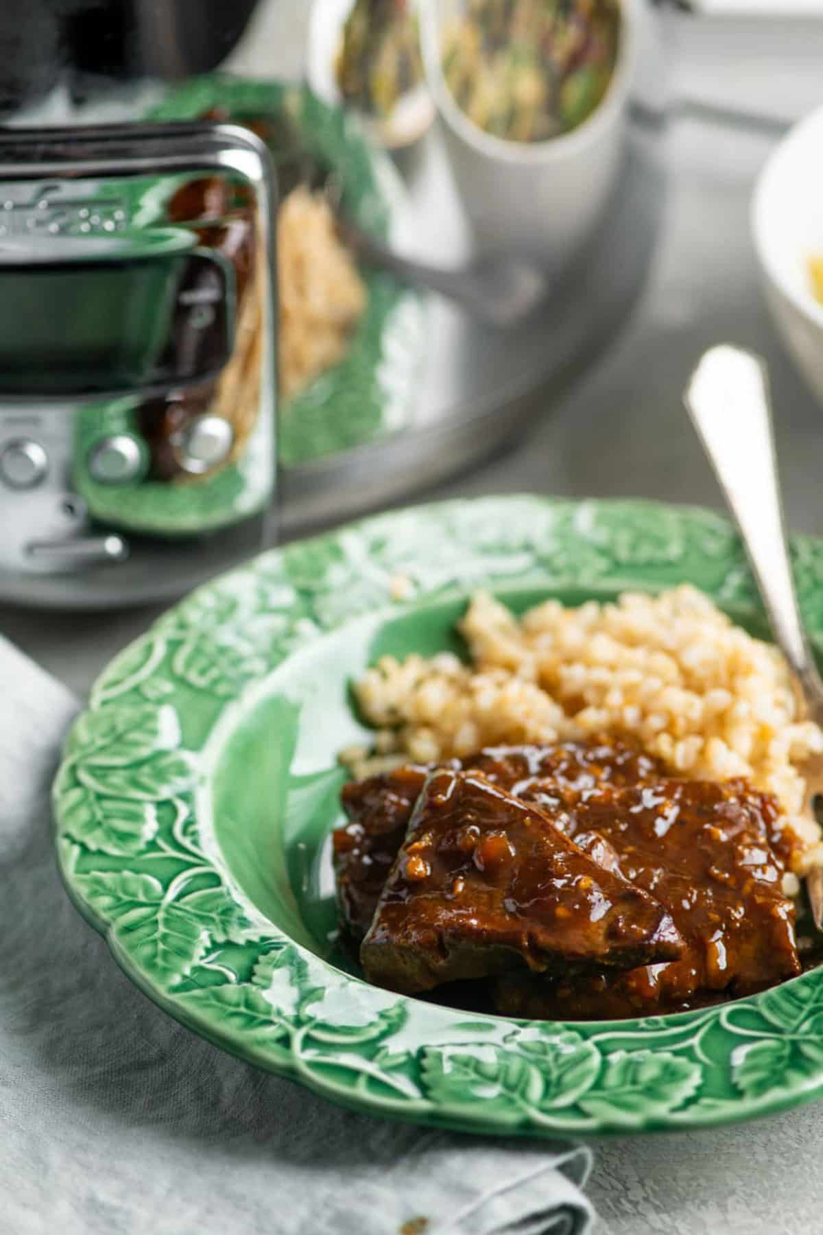 Teriyaki beef tips served over brown rice in green bowl.
