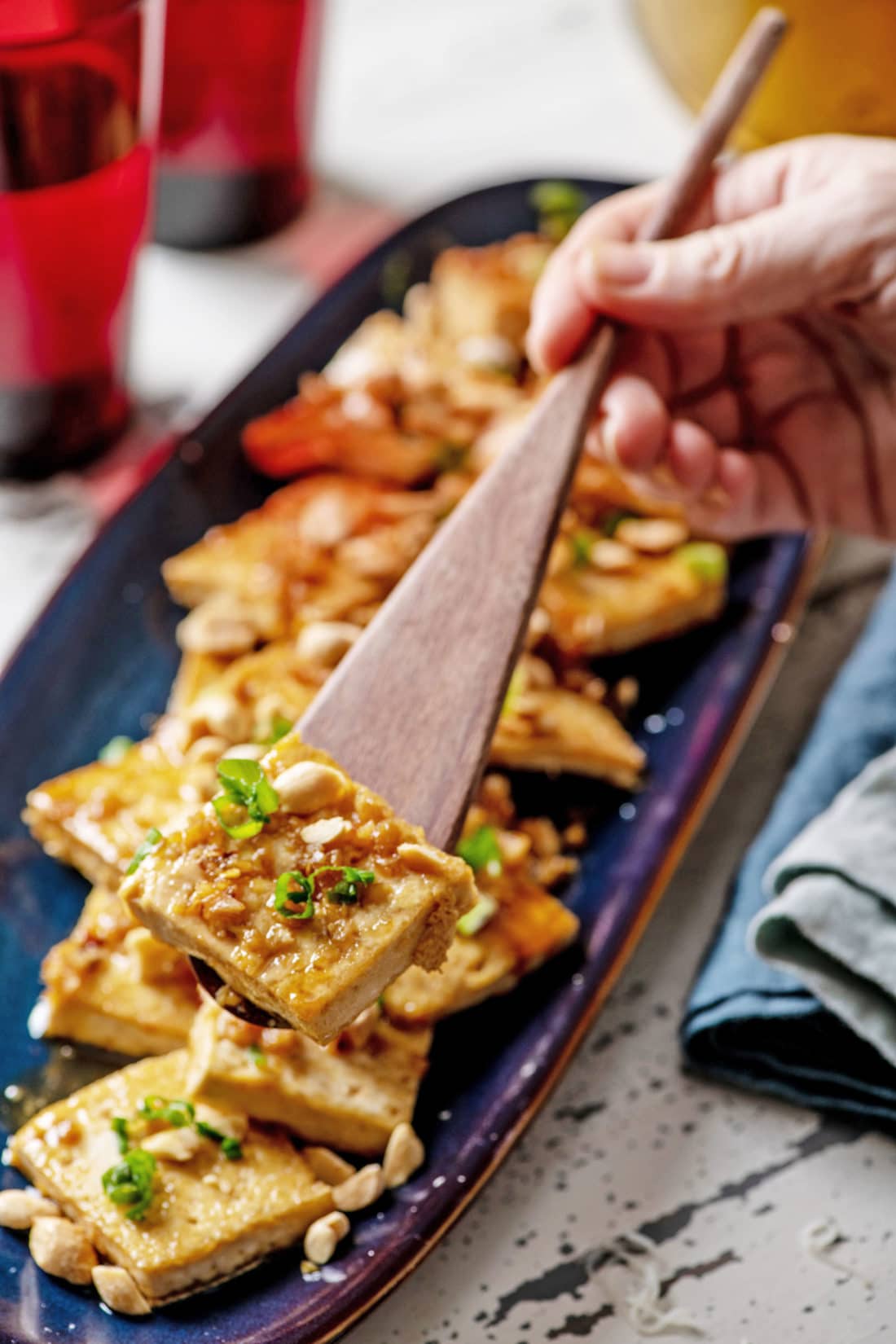 Wooden spatula with a piece of Spicy, Sweet and Nutty Tofu.