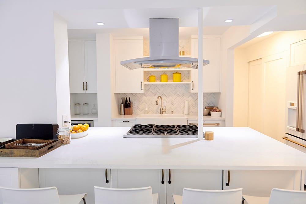 Six-burner gas stovetop on a white kitchen island set with high-top chairs.