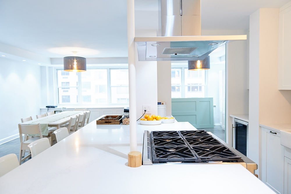 White kitchen island with a six-burner gas stovetop.