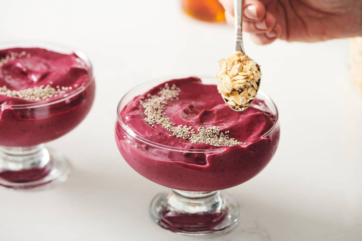 Spoon adding granola to a Beet Berry Smoothie Bowl.