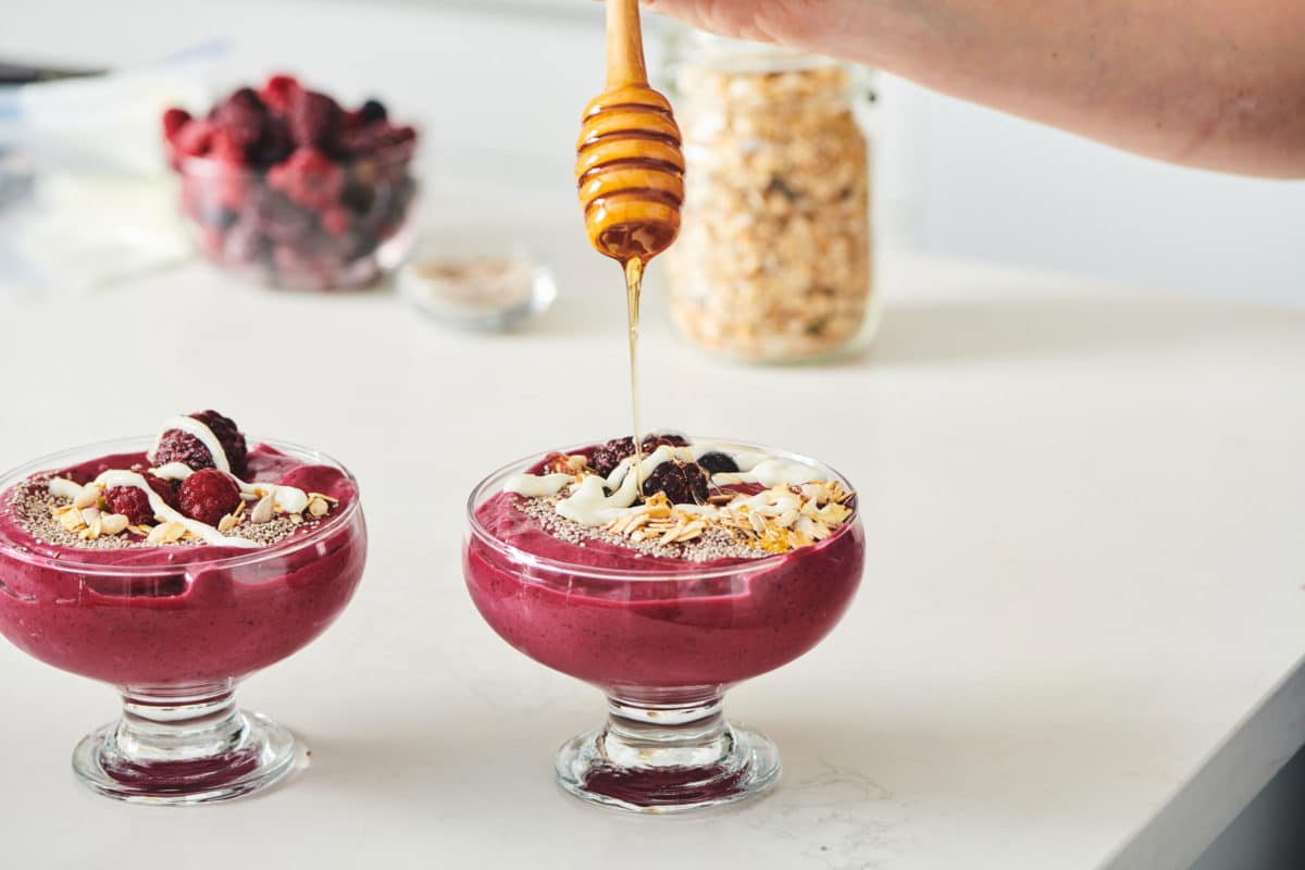 Drizzling honey over Beet Berry Smoothie Bowl