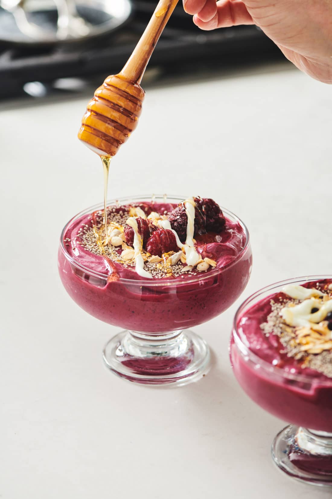 Honey being drizzled onto a Beet Berry Smoothie Bowl.