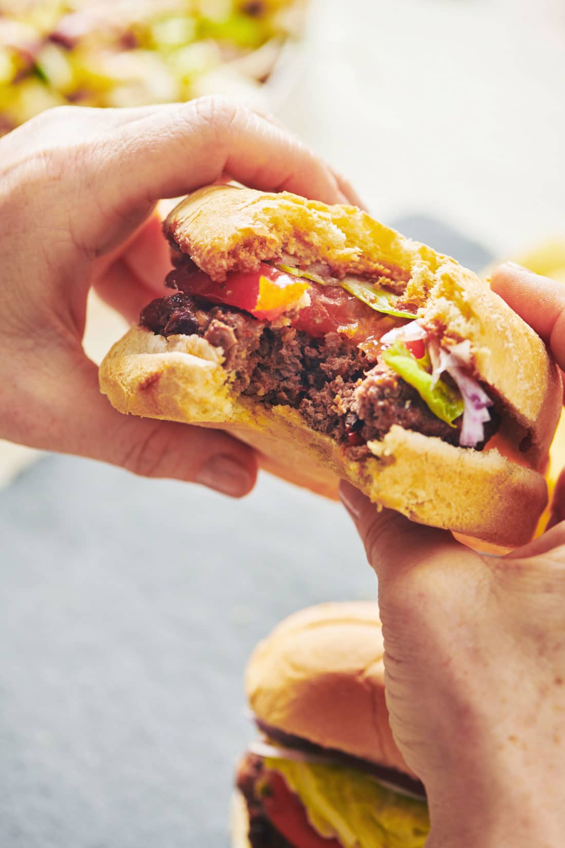 Person holding a Chipotle Beef Burger missing a bite.