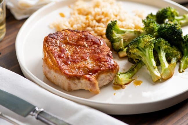 Garlicky Pork Chops and Broccoli on white plate with side dishes