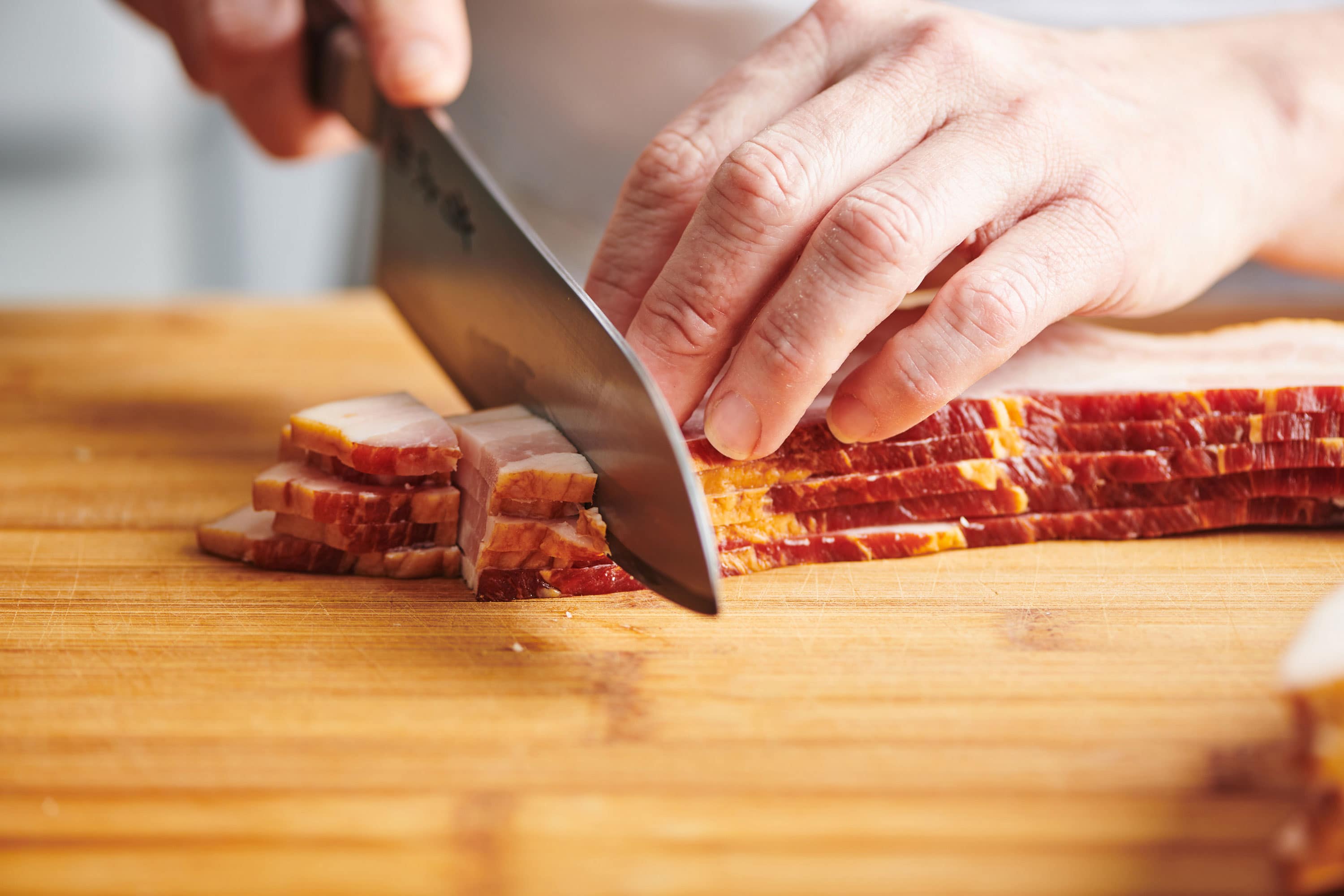 Chopping bacon into lardons with chef knife.