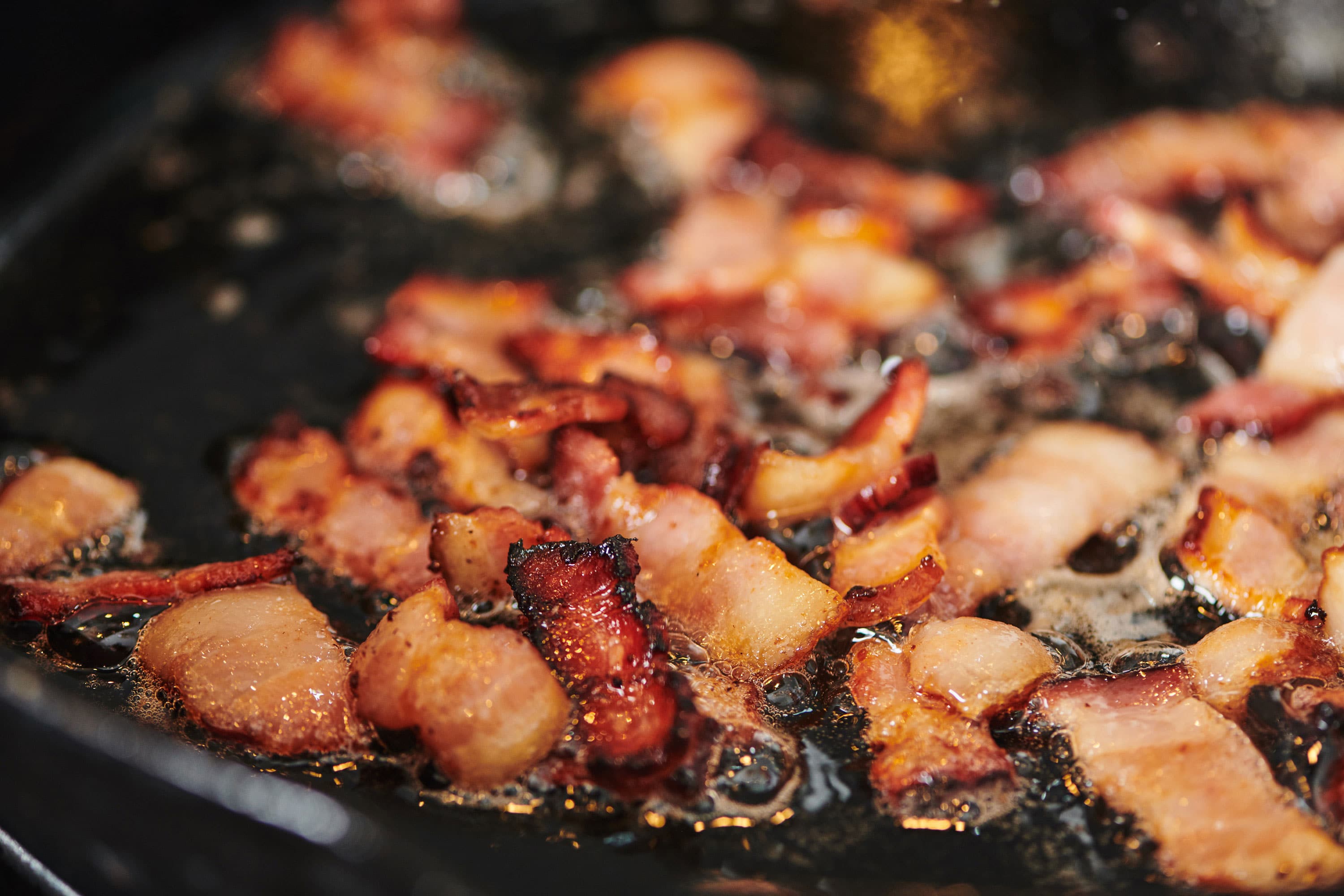 Bacon Lardons frying in pan.