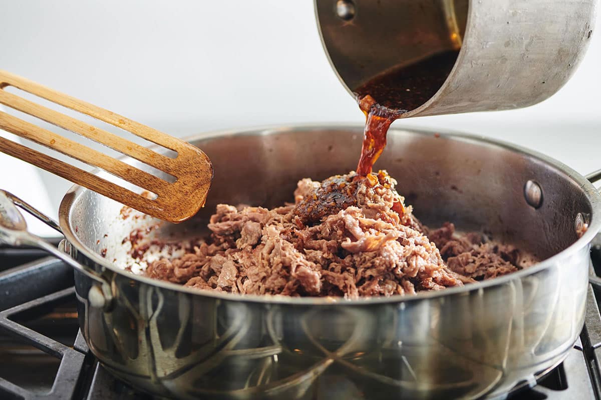Adding glaze to shredded beef for Mongolian Beef.