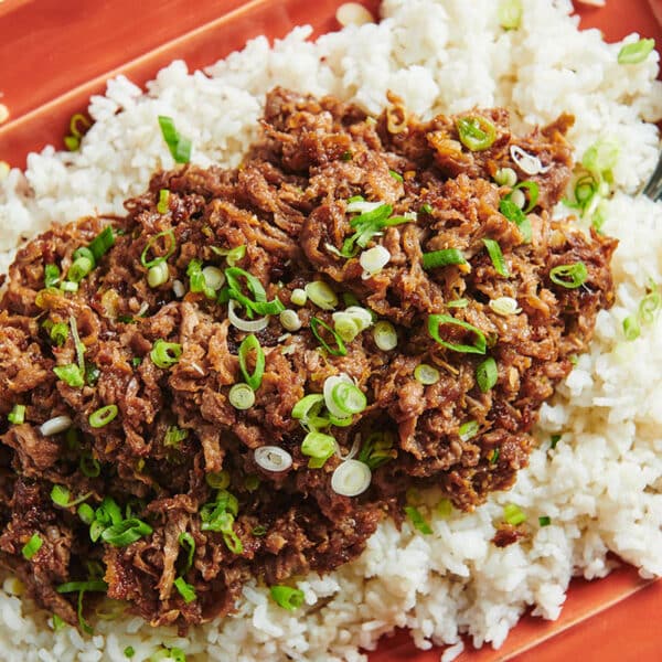Mongolian Beef over white rice on red serving plate.