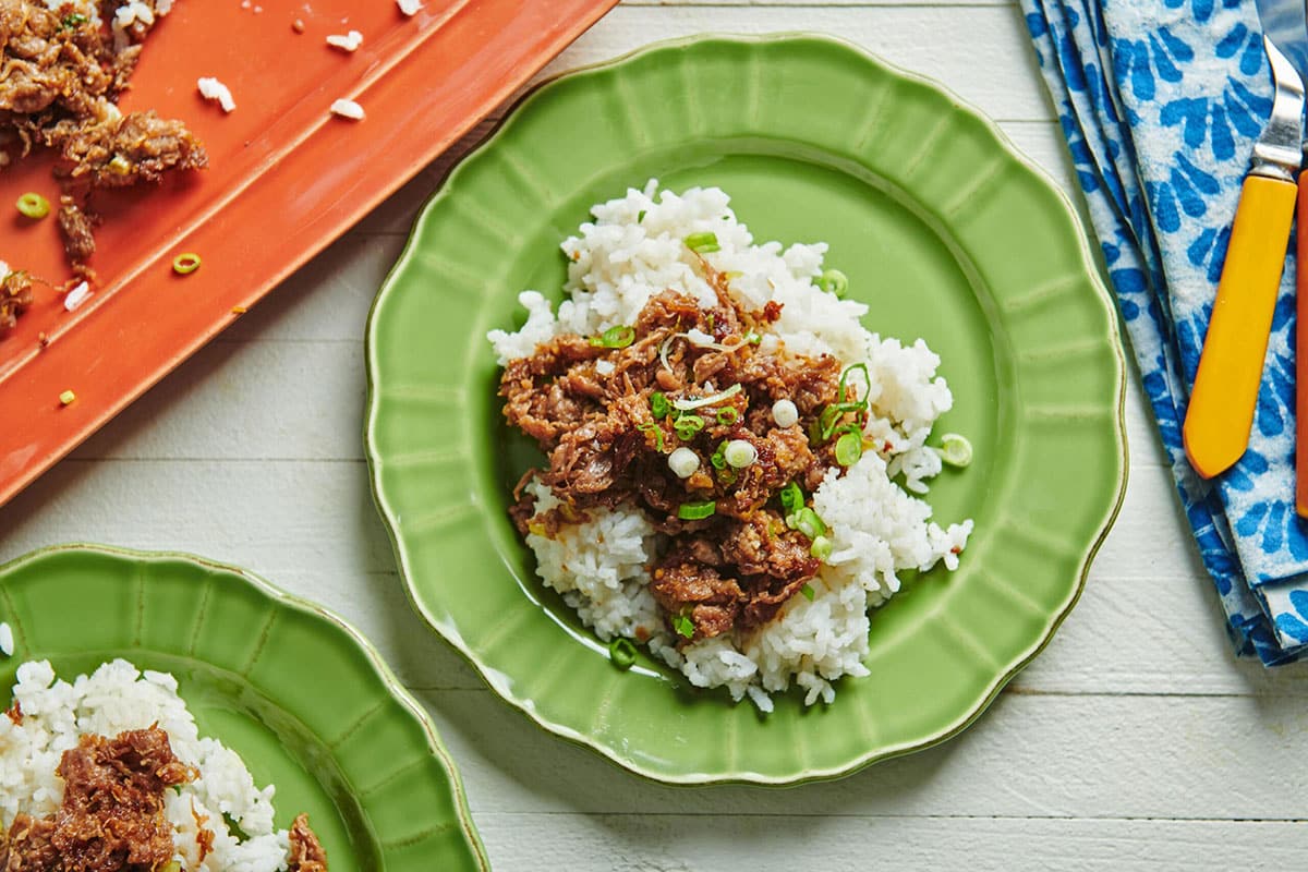 Mongolian Beef on top of rice on green plate.