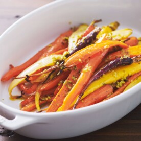 White serving dish of Roasted Carrots with Tapenade Dressing.