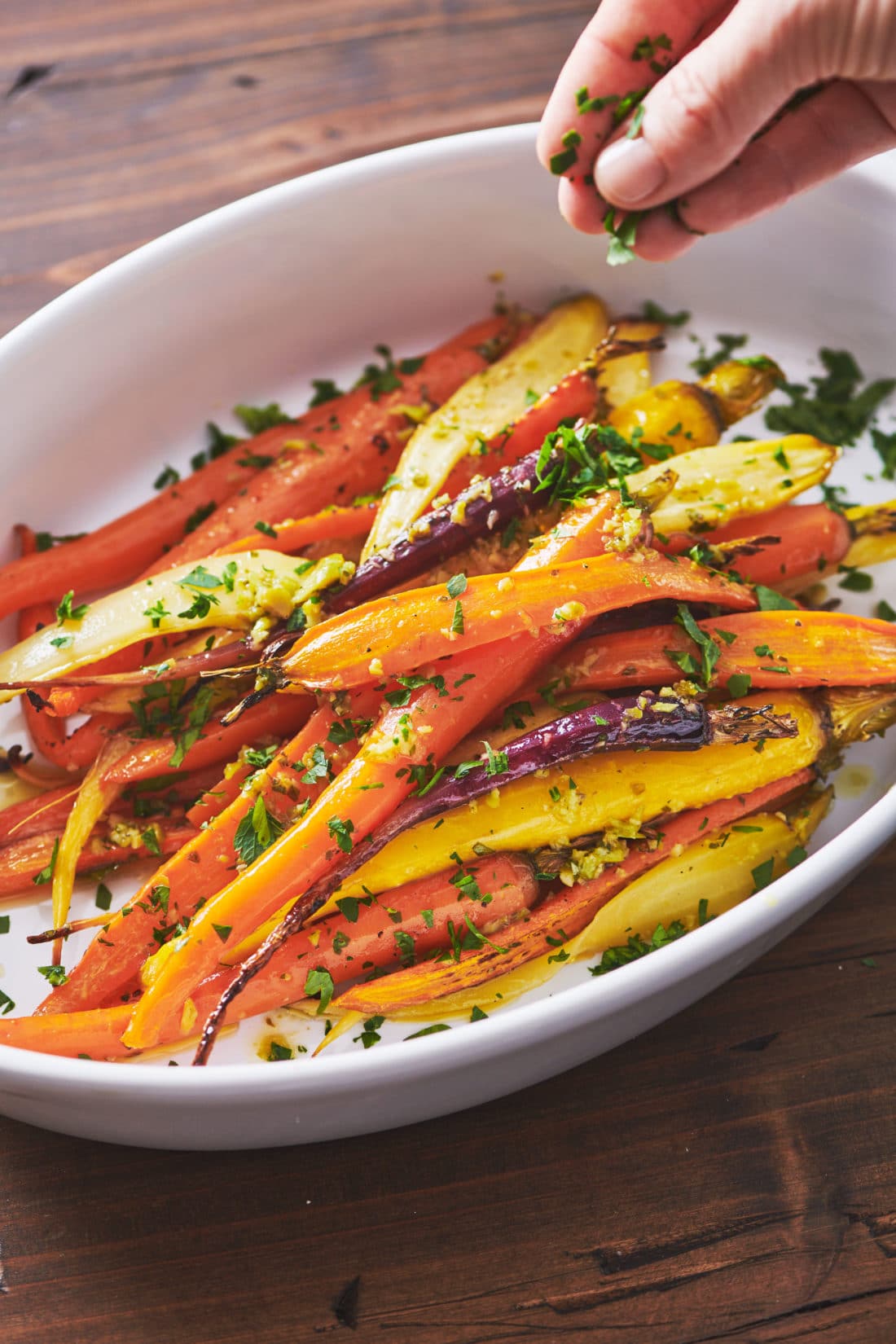 Orange, purple, and yellow Roasted Carrots with Tapenade Dressing in a bowl.