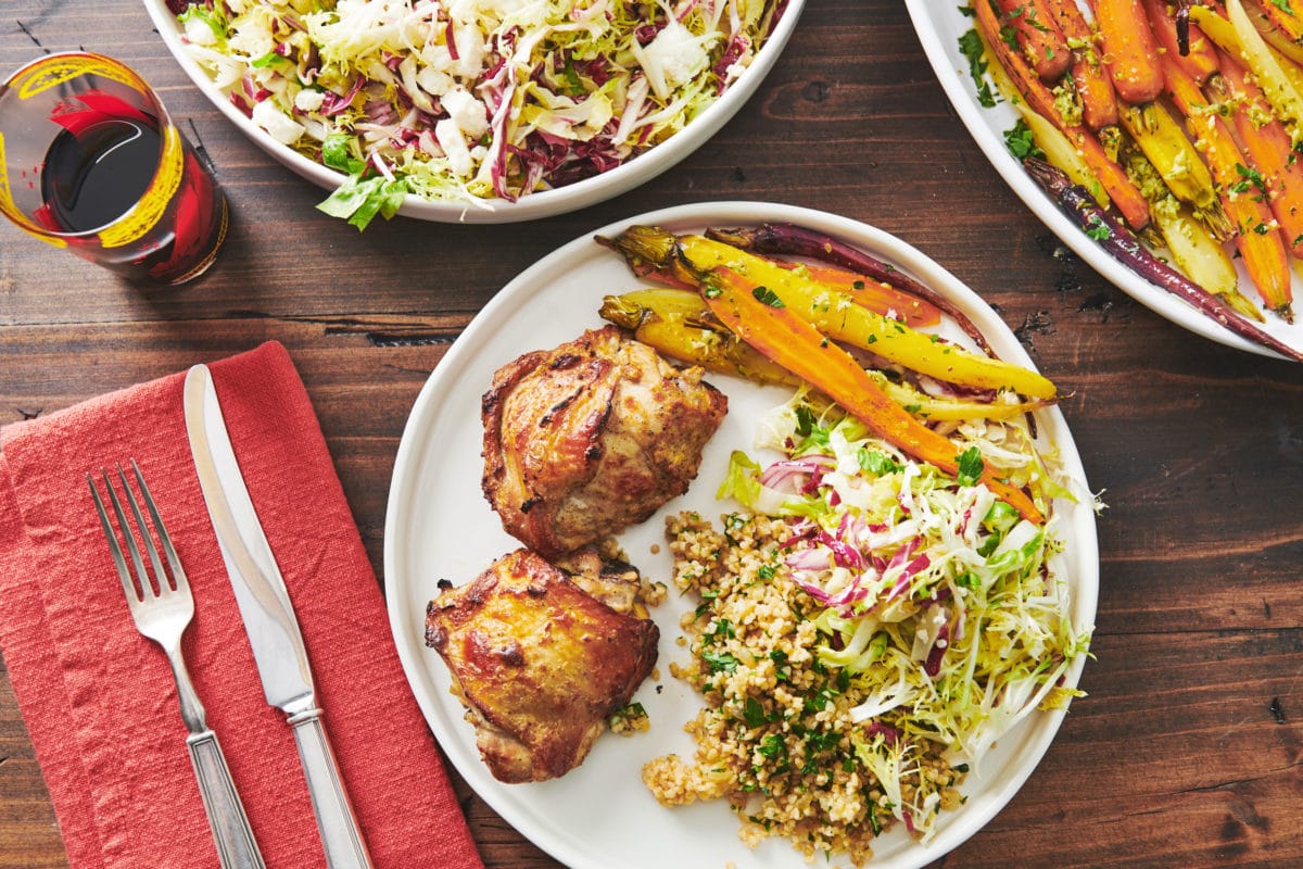 Roasted Carrots with Tapenade Dressing on a plate with salad, grains, and chicken.