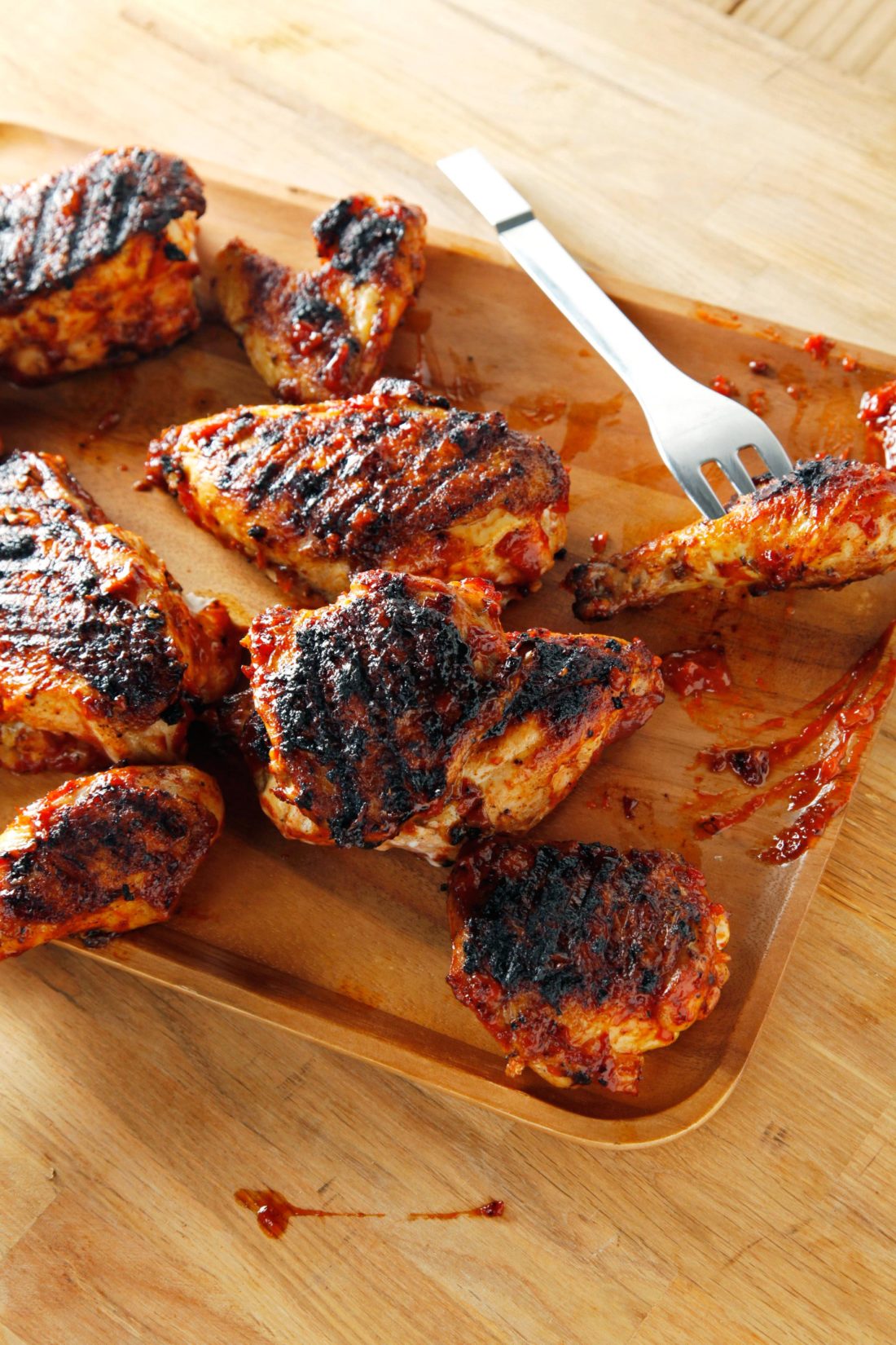Barbecued Chicken on a wooden surface with a serving fork.