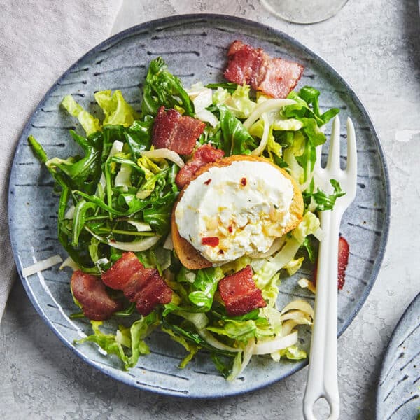 Bistro salad topped with baguetted and warm goat cheese on plate.