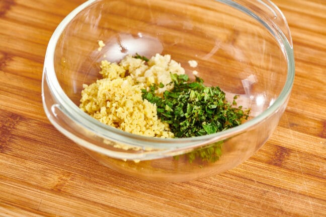 Garlic, ginger, and mint in a glass bowl.