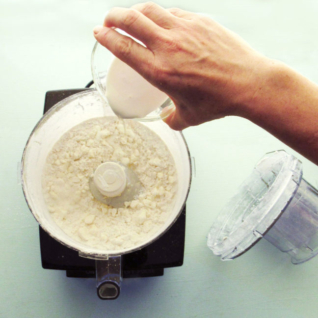 Adding the liquid to butter and flour in a food processor for a galette crust