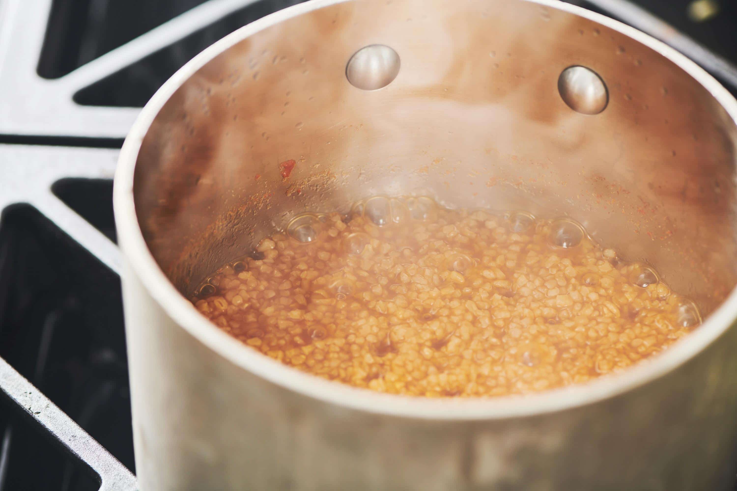 Bulgur wheat simmering in a pot on the stove.
