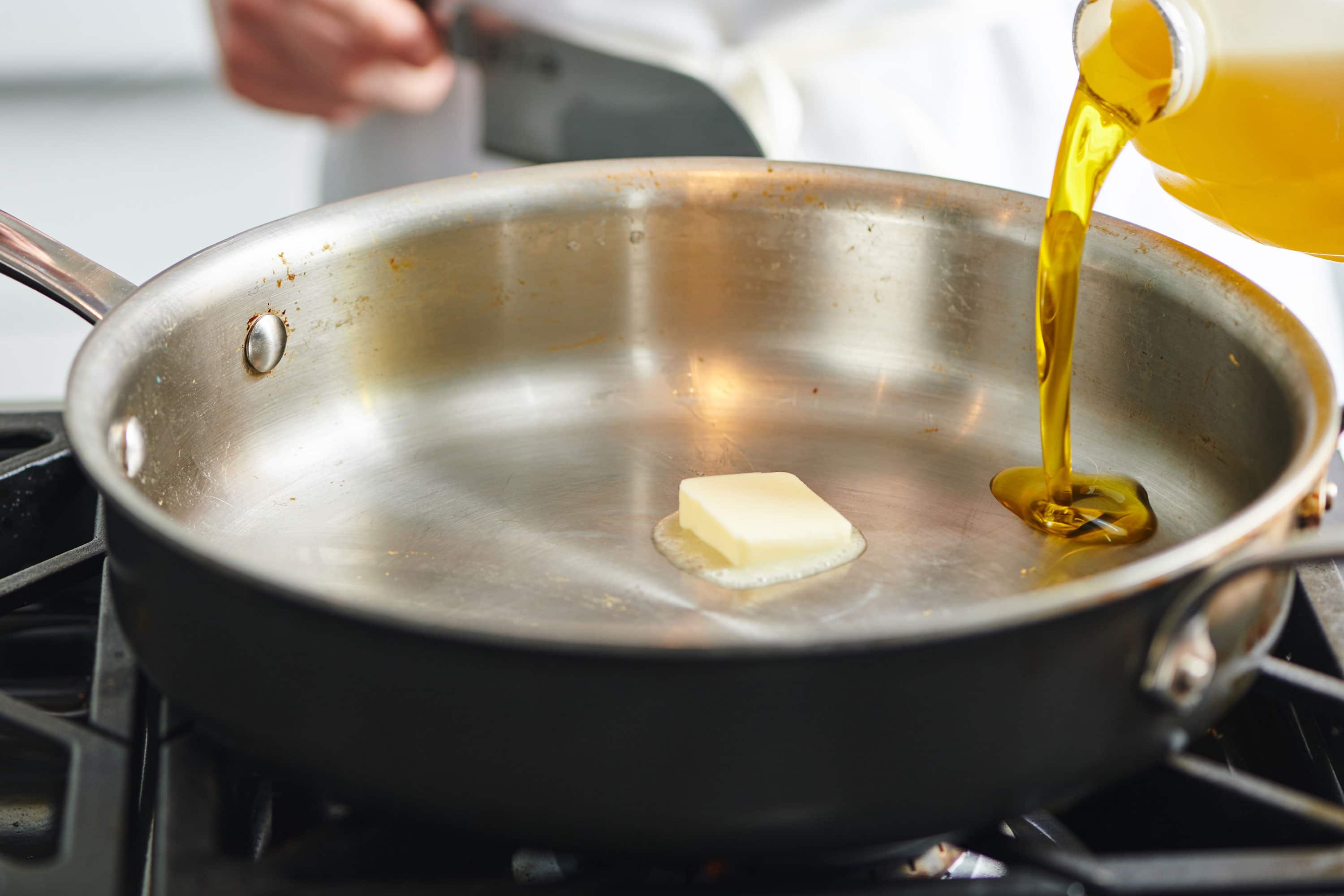 Oil being added to a pan with butter melting in it.