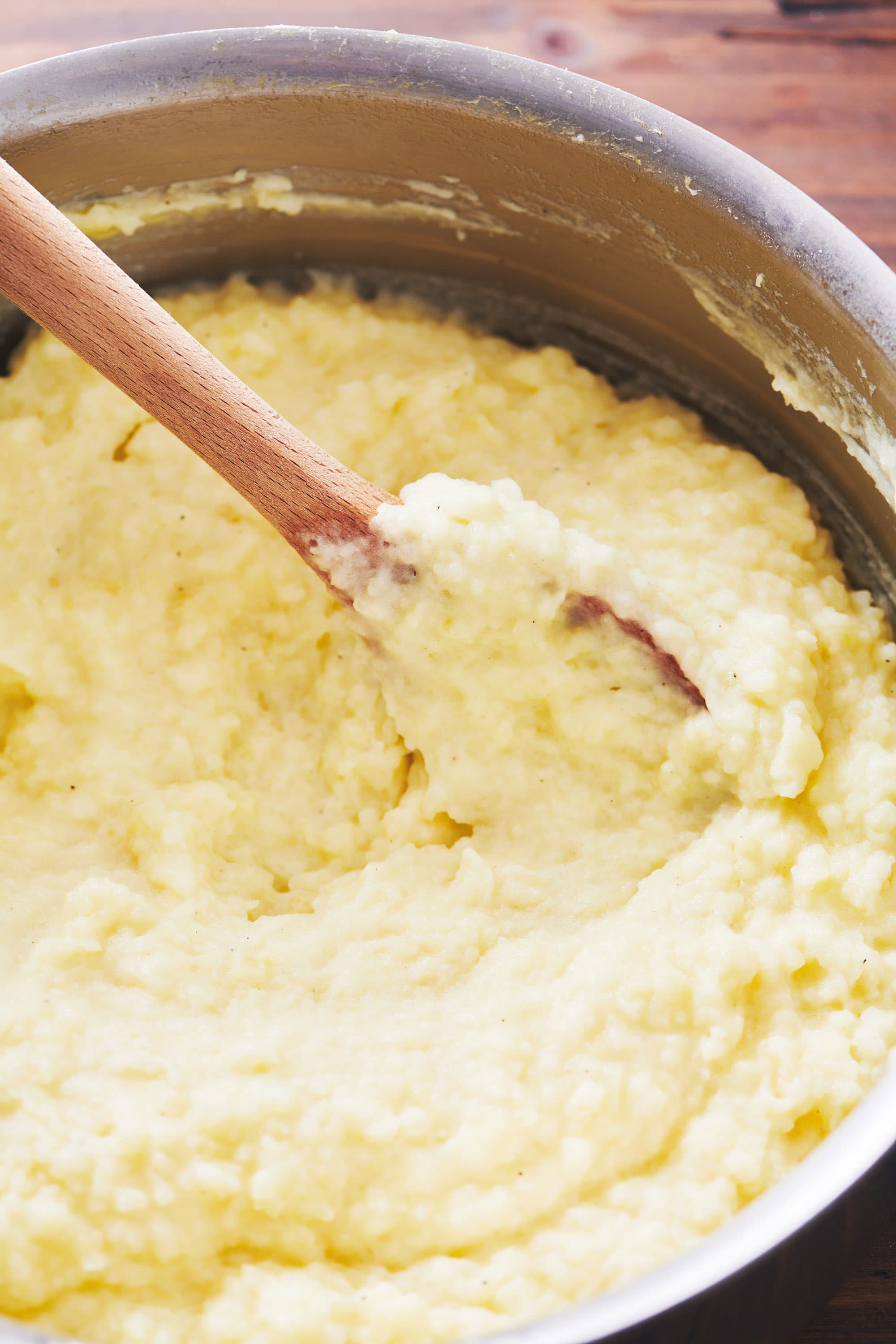 Stirring Mashed Potatoes in pot with wood spoon.